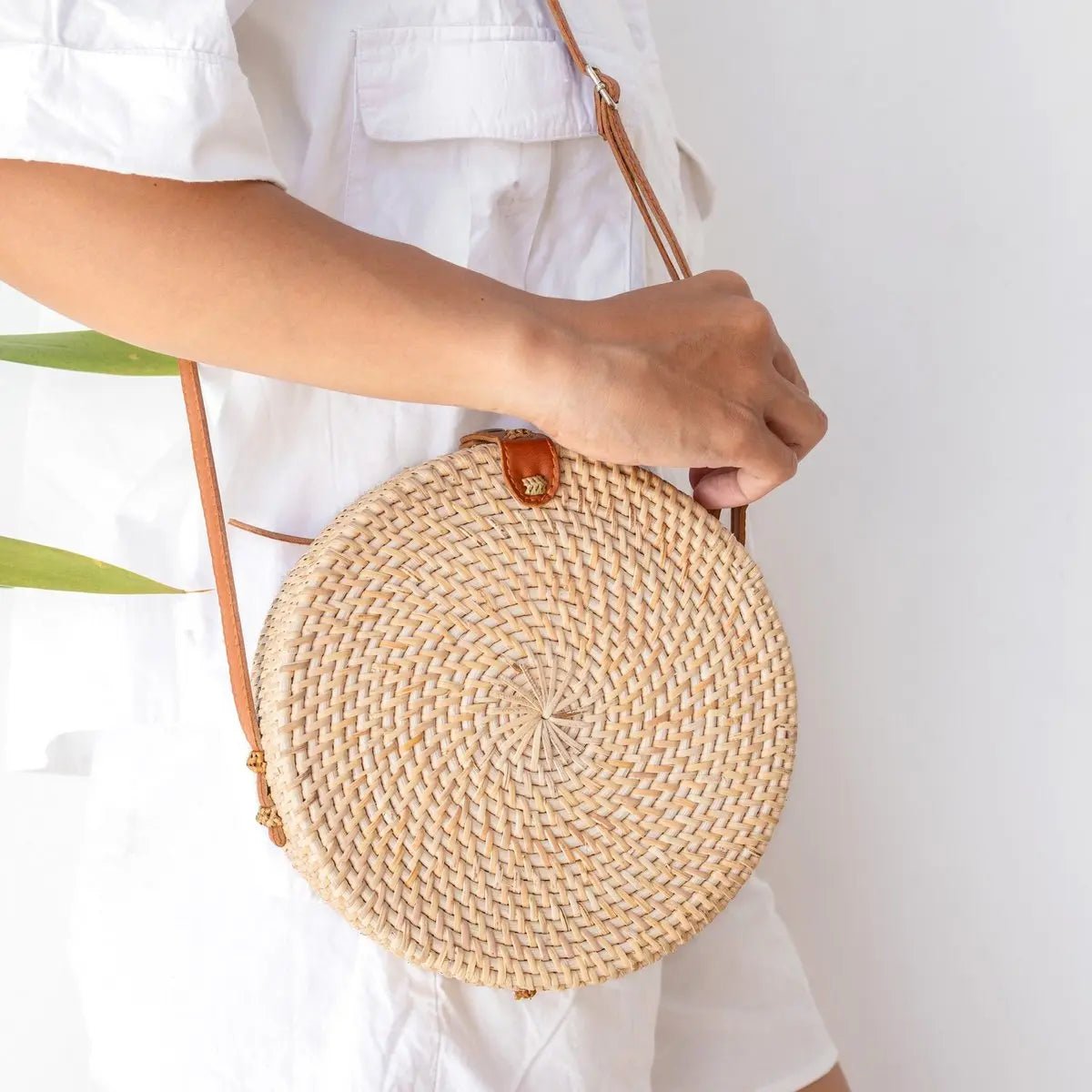 Handgemaakte ronde rotan tas SENJA in beige, Ø20 cm, hoogte 8 cm, met katoenen batikvoering en kunstleren schouderband.
